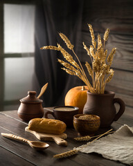 Bread, wheat and pumpkin on a dark wooden table. Village still life