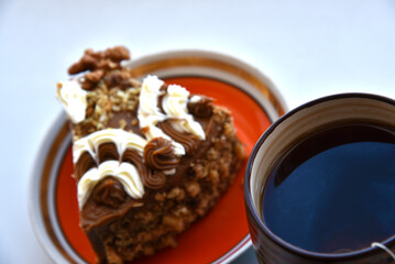 A piece of cake on a plate with nuts and tea