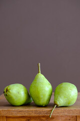 Green pears on a wooden table. Dark brown food template. Empty space. Food, ingredient, fall color, vitamin, fresh fruits, vegan ecological organic produce, healthy nutrition, vitamins, harvest.