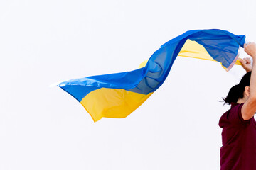 unrecognizable person running with the flag of ukraine. copy space on white background