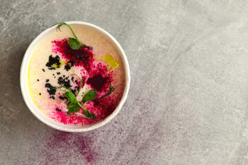Cauliflower puree potato soup in round bowl on a gray background, top view. Vegetarian healthy food delivery concept