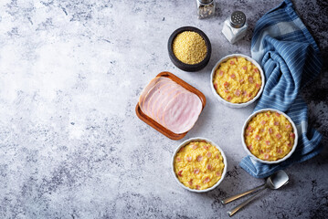 Cheesy millet with ham slices in a baking bowl
