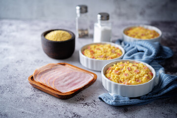 Cheesy millet with ham slices in a baking bowl