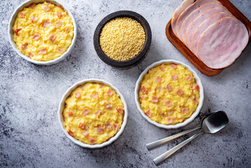 Cheesy millet with ham slices in a baking bowl