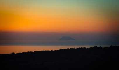 Sunset over the sea with the island of Stromboli in the background.