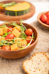 Vegetarian vegetable salad of tomatoes, pumpkin, microgreen pea sprouts on white wooden background. Side view, selective focus.
