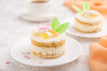 Decorated cake with milk and coconut cream with cup of coffee on a gray concrete background. Side view, selective focus.