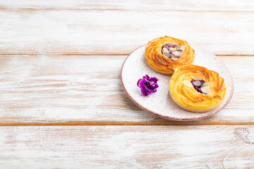 Small cheesecakes with jam and almonds on white wooden background. Side view, copy space.