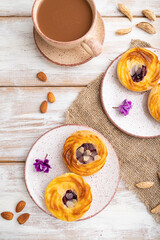 Small cheesecakes with jam and almonds with cup of coffee on a white wooden background. top view, close up.