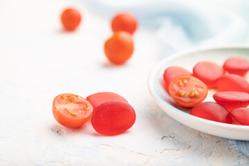 Jelly tomato candies on white concrete background. close up, side view, selective focus.