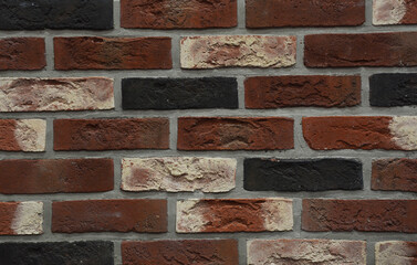 Clinker bricks background. A close-up of a clinker brick wall from dark red, white, orange and...