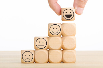 Hand chooses smiley face on wooden block. Excellent business service rating customer experience. Satisfaction survey concept