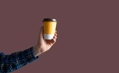 hand holding a blank coffee paper cup for takeaway outside in the street