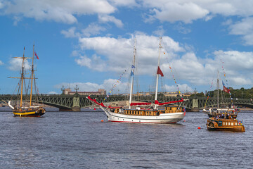 Fototapeta premium several old sailing ships parked on the Neva River in St. Petersburg against the blue sky and city