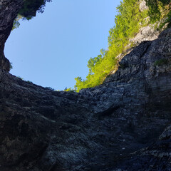 Bottom view of the hill with the dense greenery on the top against a clear blue sky on a sunny day