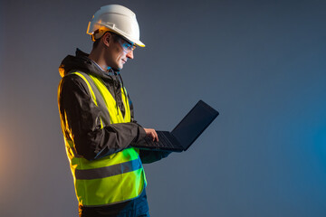 Computer engineer. Builder stands with laptop. Construction worker in yellow vest and helmet....