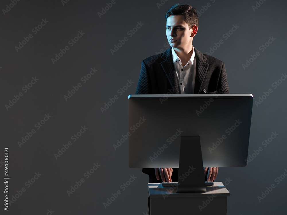 Poster man at computer. businessman stands next to computer. manager is typing while standing. businessman 