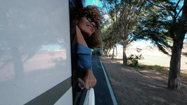 Happiness and freedom travel lifestyle concept with joyful and cheerful pretty adult woman smile and have fun outside the window of her modern camper car van. Road trip in holiday vacation people life