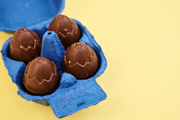 Chocolate eggs in blue box on yellow background with cope space, Happy Easter