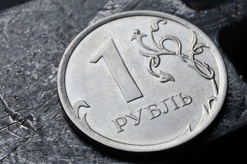 Russian coin denominated 1 ruble. shines on a scratched metal surface. close-up. translation of the text on the coin "1 ruble"