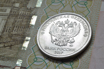 Russian coin with a face value of 1 ruble lies on a banknote. Translation of the inscriptions on...