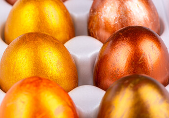 Close-up of Easter painted eggs in gold and bronze in a white package.