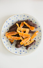 Closeup of candied orange rind dipped in chocolate on antique plate with blue flowers
