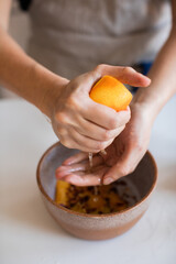 Closeup of woman squeezing fresh orange juice into a bowl with her hands