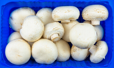 White champignon mushrooms from the store in a box. Vegan food.