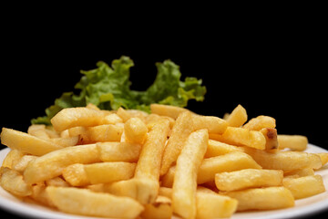 Fried potatoes with lettuce, on a black background