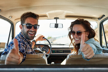 Thumbs up for roadtrips. Rearview portrait of an affectionate couple giving you a thumbs up while...
