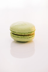 Colorful cake macaroons isolated on abstract background. Traditional French multicolored macaroon. Green macaron pastries on white background. Food concept.