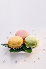 Multicolor macarons , french macaroon, greedy pastry. Macarons on white reflective glass, sweet tasty desserts. French dessert sweets colored macaroons cookies arranged on a while plate
