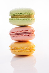 Vertical stack of three macarons against a bright white background. Sweet colorful macarons isolated on white background. Tasty colourful macaroons
