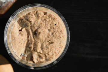 Active rye and wheat sourdough starter in glass jar. Top view, selective focus