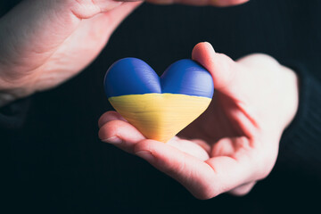 Heart flag of Ukraine in human hands. No war, peace for Ukraine concept.