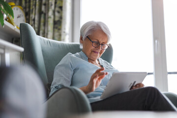 Senior woman using a digital tablet at home
- 494079952