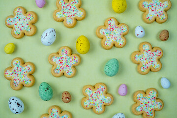 Easter flower biscuits and candy eggs on flat colored background .Easter holiday candy concept.