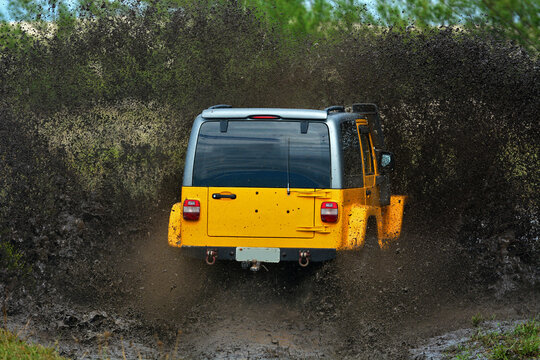 Yellow brazilian off-road sport truck splashing on a muddy puddle road