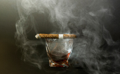 Whiskey drinks with cigars from Cuba Havana on black background. A glass of whiskey or cognac with...