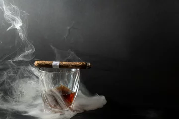 Foto op Canvas Whiskey drinks with cigars from Cuba Havana on black background. A glass of whiskey or cognac with a Smoking cigar lying on top. Front view. © Василь Івасюк