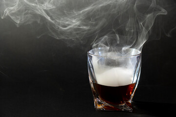 Whiskey drinks isolated on black backdrop. Close up view of a glass of whiskey on a black slate with a smoky background.
