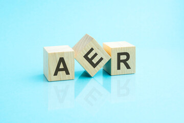three wooden cubes with the letters AER on the bright surface of a blue table