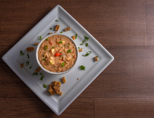 Vegan food, Mashed Beans , Called Tutu, in a bowl on a white plate, over wooden surface, top view.