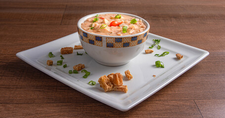Vegan food, Mashed Beans , Called Tutu, in a bowl on a white plate, over wooden surface, selective focus.