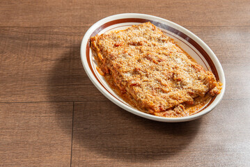 Vegan food, Lazanha de chimeji, in a clear bowl on wooden surface, selective focus.