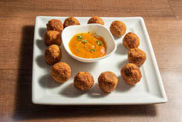 Vegan food, chickpea meatball and sauce, on a white plate over wood, selective focus.