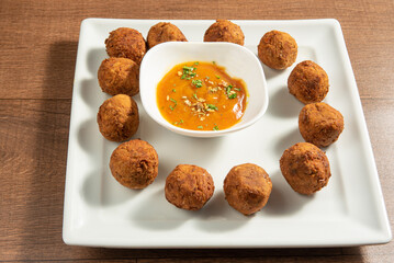 Vegan food, chickpea meatball and sauce, on a white plate over wood, selective focus.