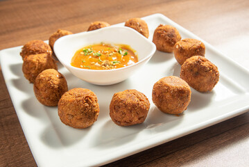 Vegan food, chickpea meatball and sauce, on a white plate over wood, selective focus.