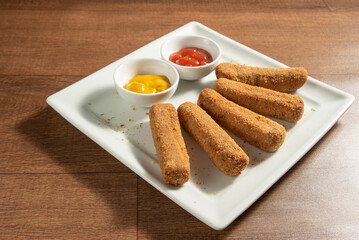 Vegan food, chickpea croquette and sauces on a white plate over wood, selective focus.